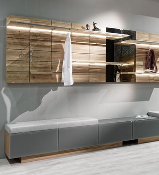 Holzbank mit weißem Leder Garderobenpaneele aus Holz und weise Holzschränke in der Diele