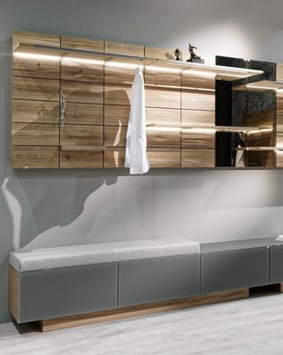 Holzbank mit weißem Leder Garderobenpaneele aus Holz und weise Holzschränke in der Diele