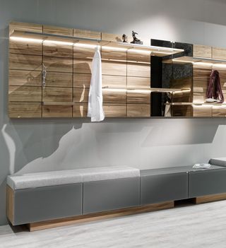 Holzbank mit weißem Leder Garderobenpaneele aus Holz und weise Holzschränke in der Diele