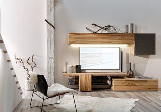 Stuhl und weißer Teppisch vor Holzwohnwand und Fernseher