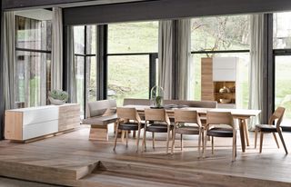langer Holztisch mit Holzstühlen mit hellbrauner Ledersitzfläsche vor weißem Sideboard und Holzschrank