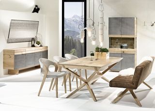 Heller Holztisch mit brauner Sitzbank und grauen Stühlen vor Holzschrank und Sideboard mit Eisen Front