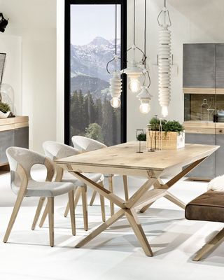 Heller Holztisch mit brauner Sitzbank und grauen Stühlen vor Holzschrank und Sideboard mit Eisen Front