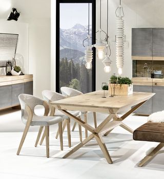 Heller Holztisch mit brauner Sitzbank und grauen Stühlen vor Holzschrank und Sideboard mit Eisen Front