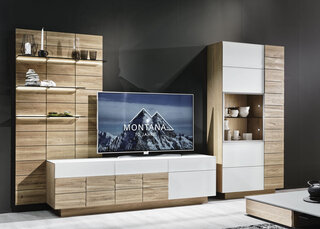 Dunkles Sofa und Teppisch vor Holzwohnwand mit grauem Hängeelement und Fernseher