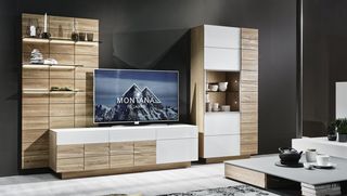 Dunkles Sofa und Teppisch vor Holzwohnwand mit grauem Hängeelement und Fernseher