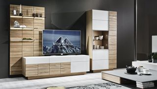 Dunkles Sofa und Teppisch vor Holzwohnwand mit grauem Hängeelement und Fernseher