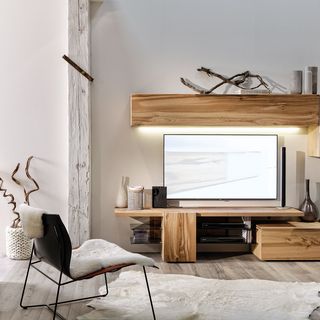 schwarzer Stuhl vor Wohnwand aus Holz mit Fernseher