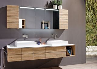 Badezimmer mit Spiegelschrank Waschbecken und Hängeelement aus hellem Holz