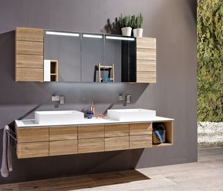 Badezimmer mit Spiegelschrank Waschbecken und Hängeelement aus hellem Holz