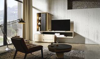 Stehlampe Wohnsessel und Abstelltisch vor Wohnwand aus hellem Holz mit schwarzen Details