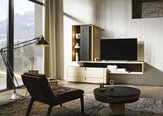 Stehlampe Wohnsessel und Abstelltisch vor Wohnwand aus hellem Holz mit schwarzen Details